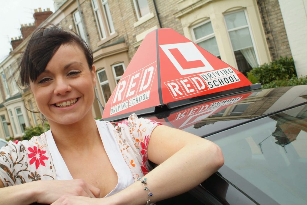 woman and red driving school car sign
